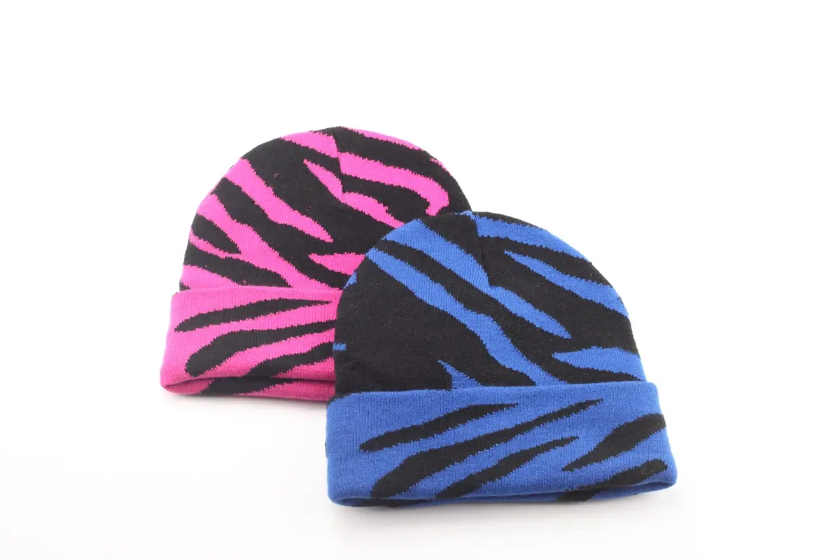 Two rib-knit beanies with pink and blue striped patterns arranged together