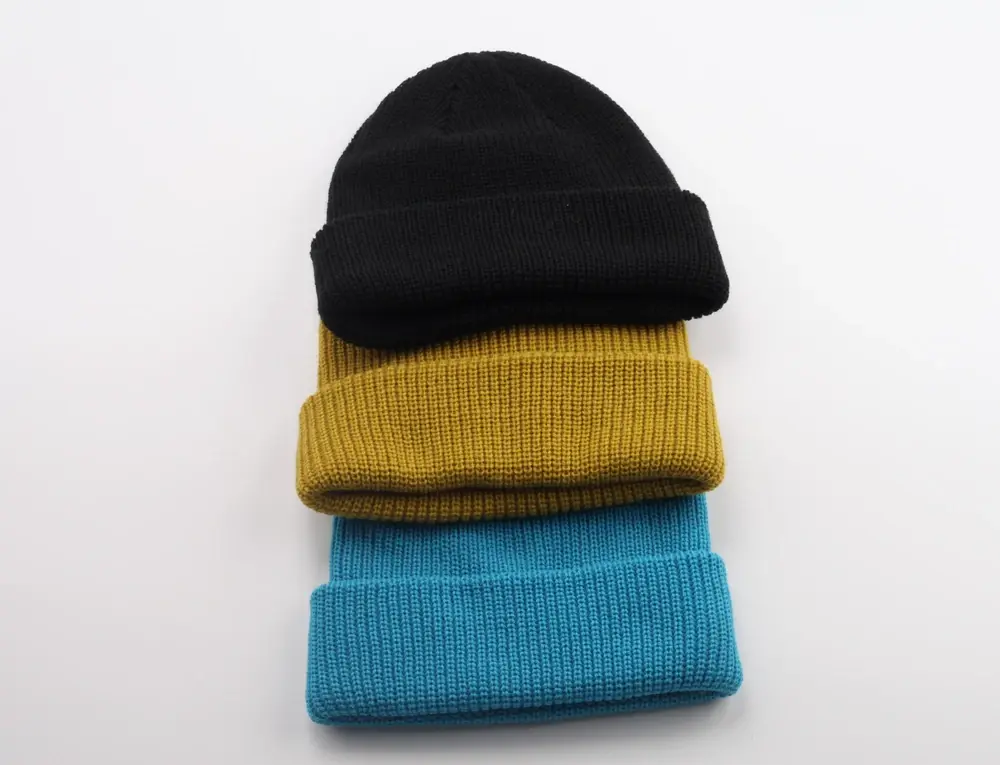 Three rib-knit beanies in black, mustard and blue stacked together