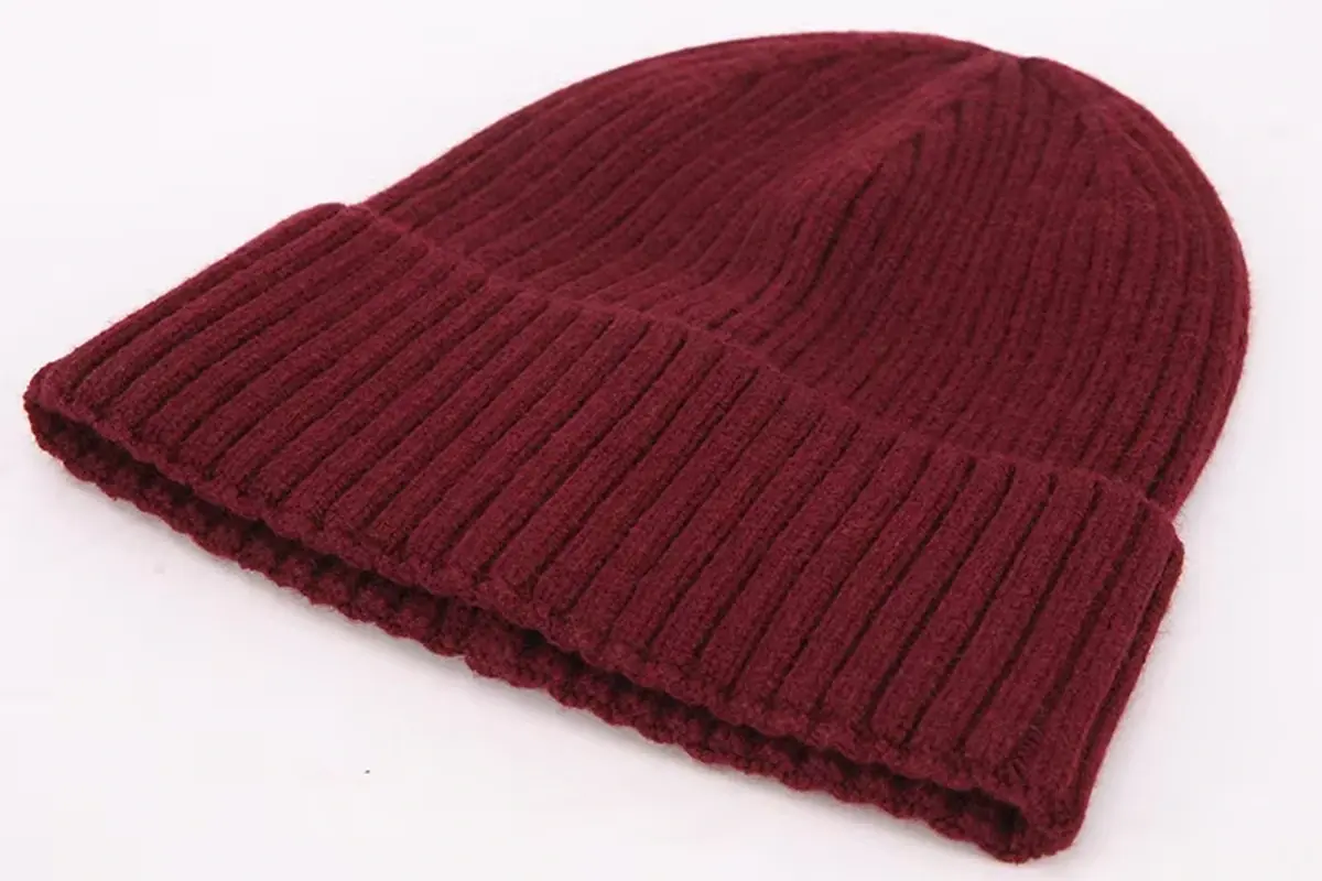 Burgundy rib-knit beanie resting on a light surface.