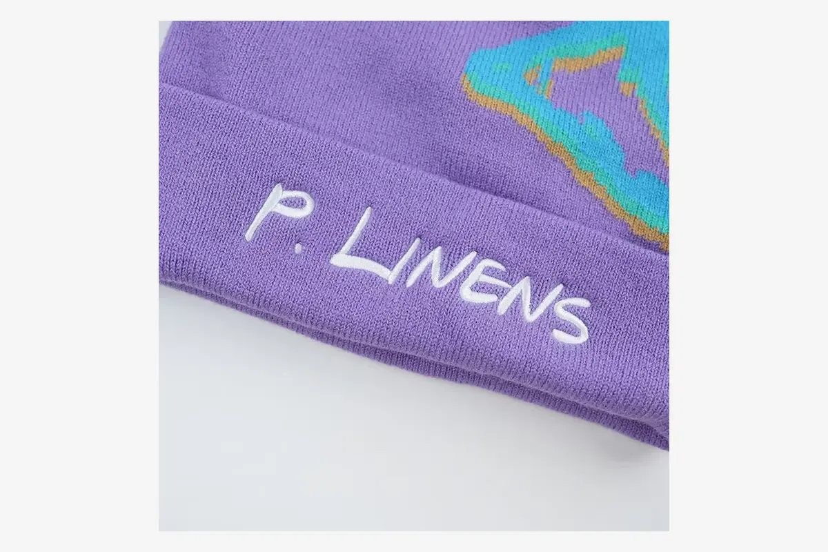 Close view of white embroidered lettering on a purple knit cuff.