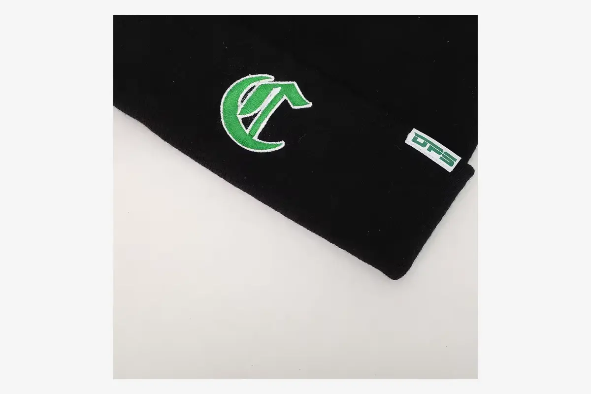 Close view of a white side tab label sewn into a black beanie.