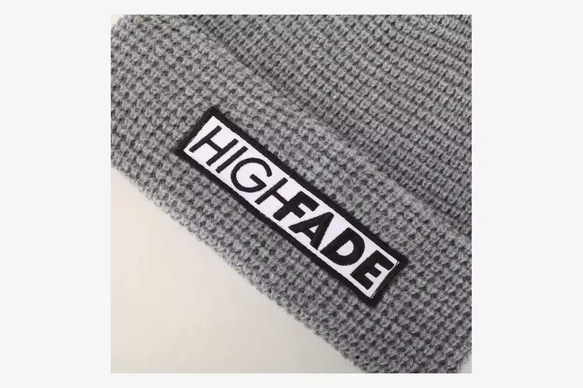 Close view of a rectangular woven patch stitched to gray knit.
