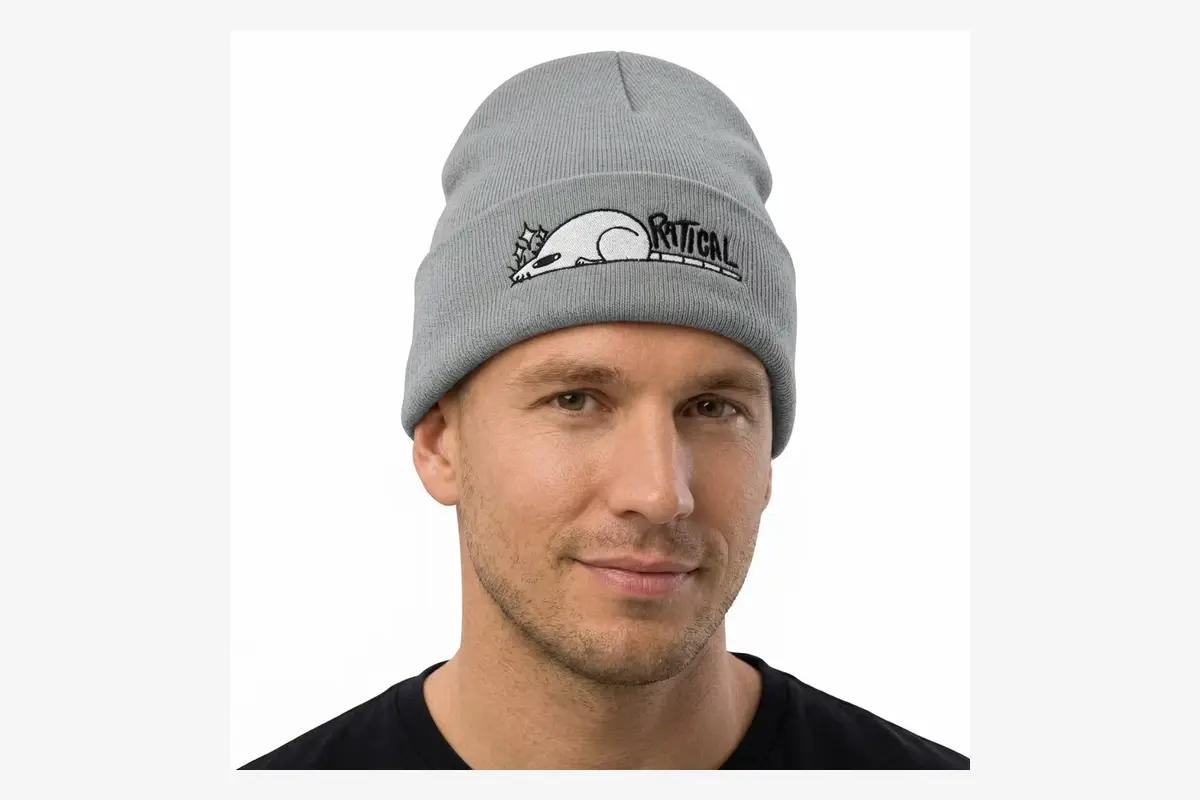 Man wearing a gray embroidered beanie to assess fit and logo position.