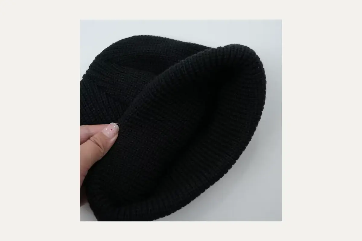 Black knit beanie showing its soft inner layer.