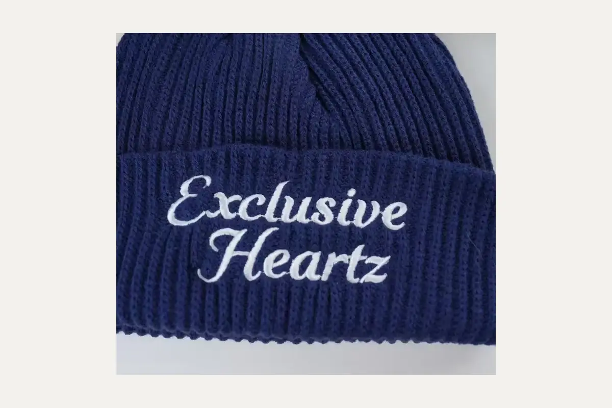 Navy knit beanie with white embroidered lettering.