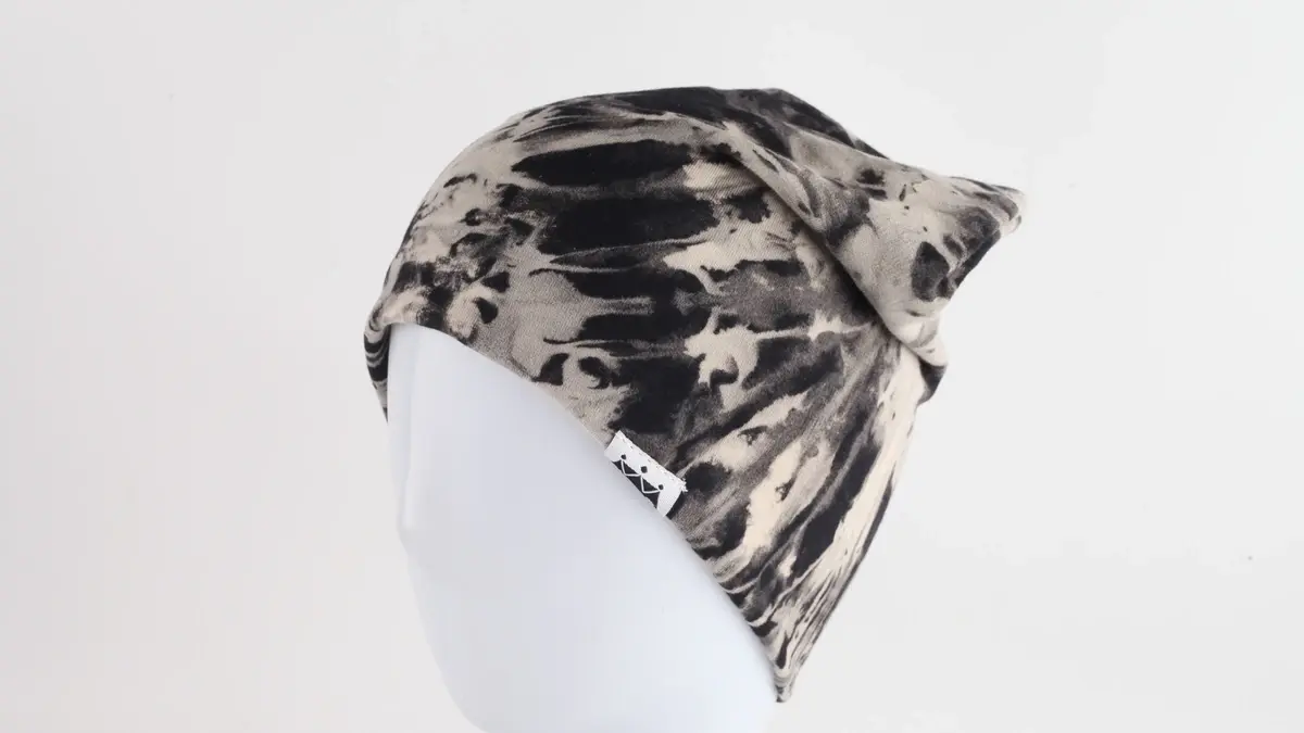 Black-and-white camouflage knit beanie on a white display head.