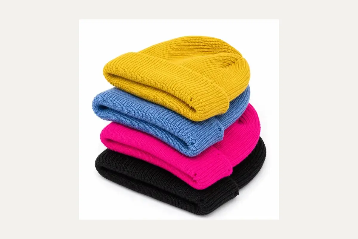 Stack of finished knit beanies in several colors.