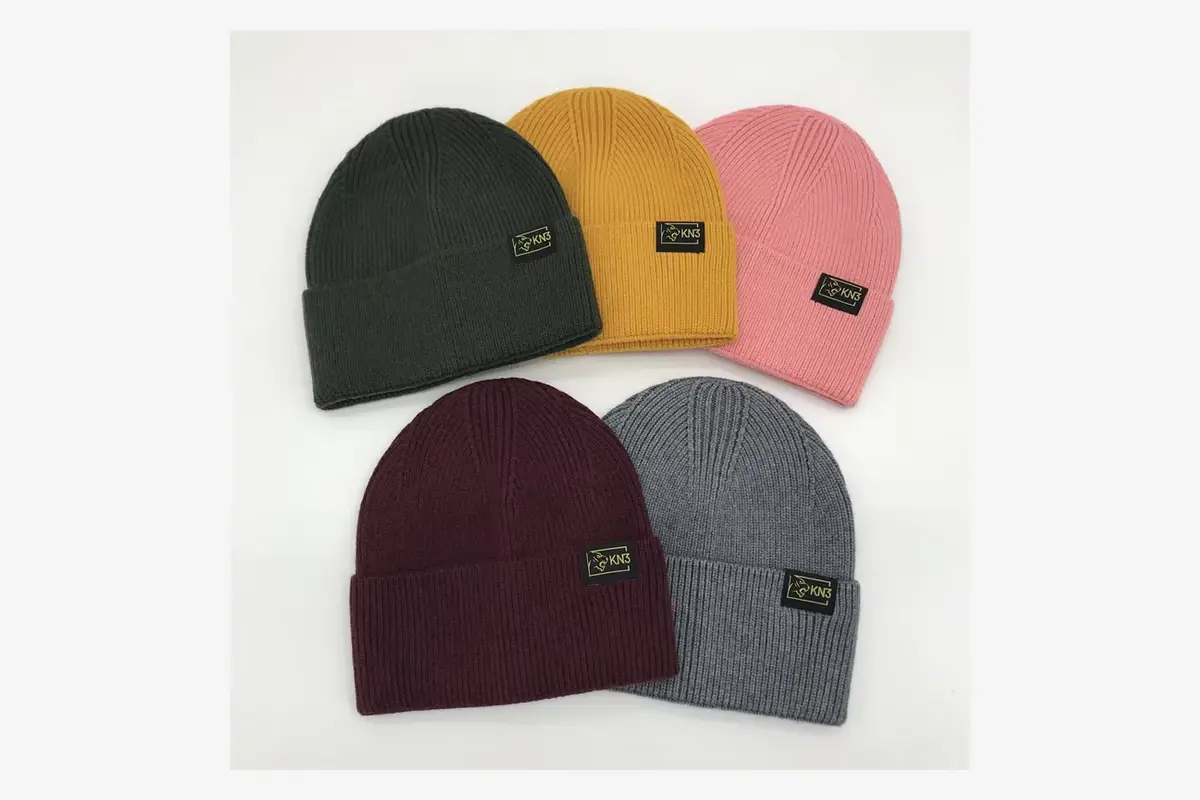 Five cuffed beanies in different colors with matching sewn labels.
