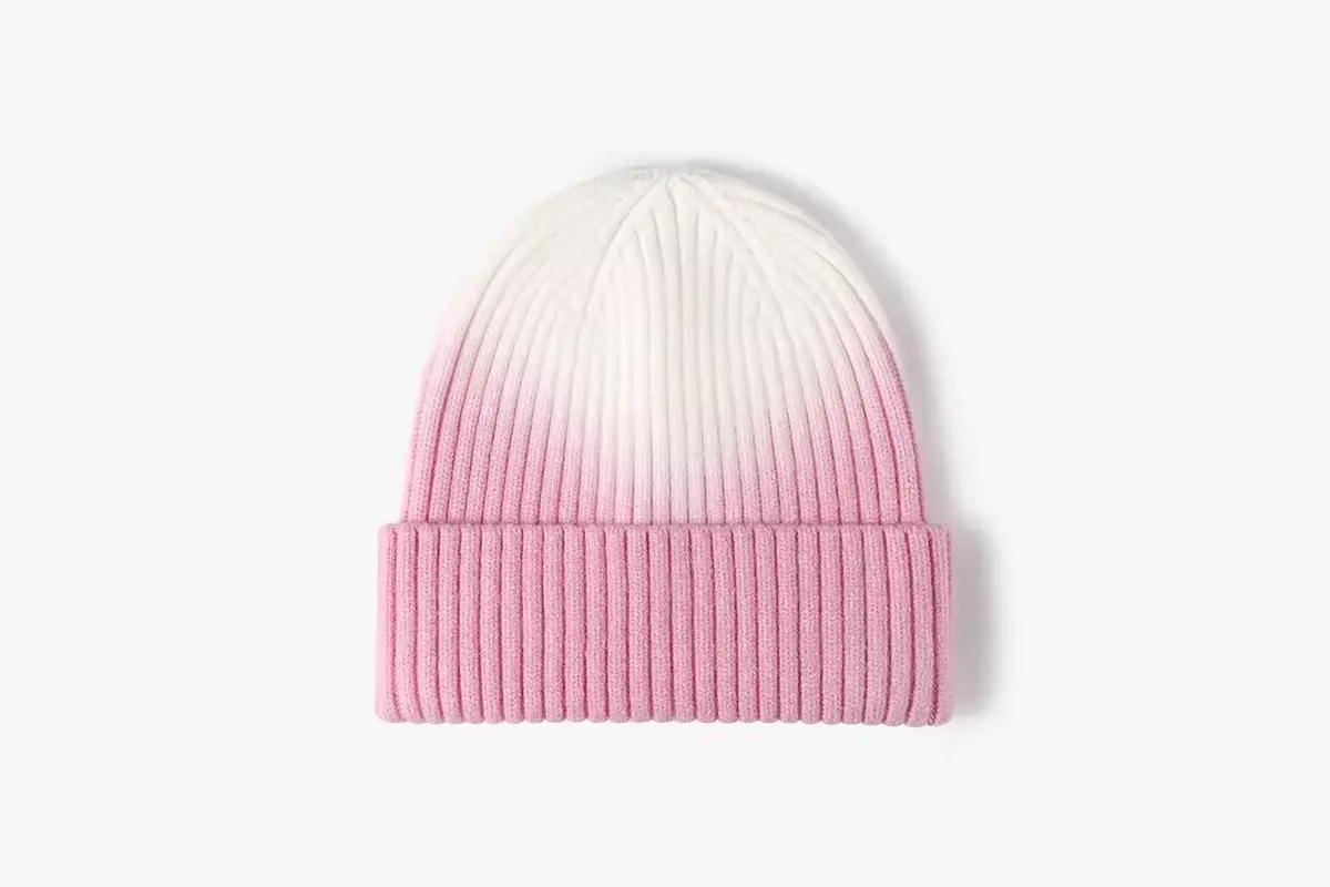 Pink and white rib-knit cuffed beanie laid flat.