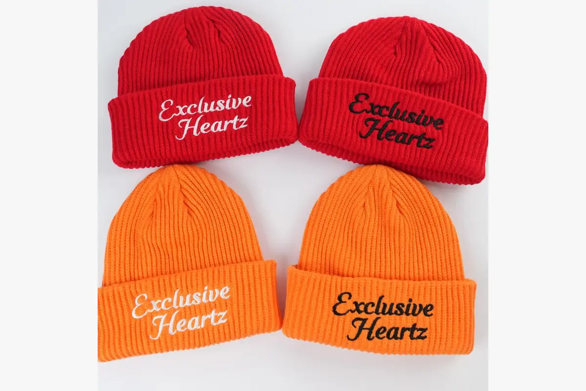 Four red and orange cuffed beanies showing embroidered logos on the folded cuffs