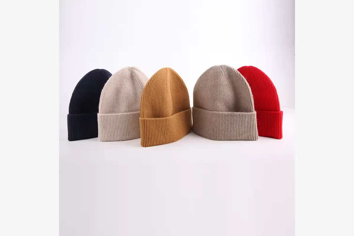 Five plain cuffed beanies in neutral and red colors
