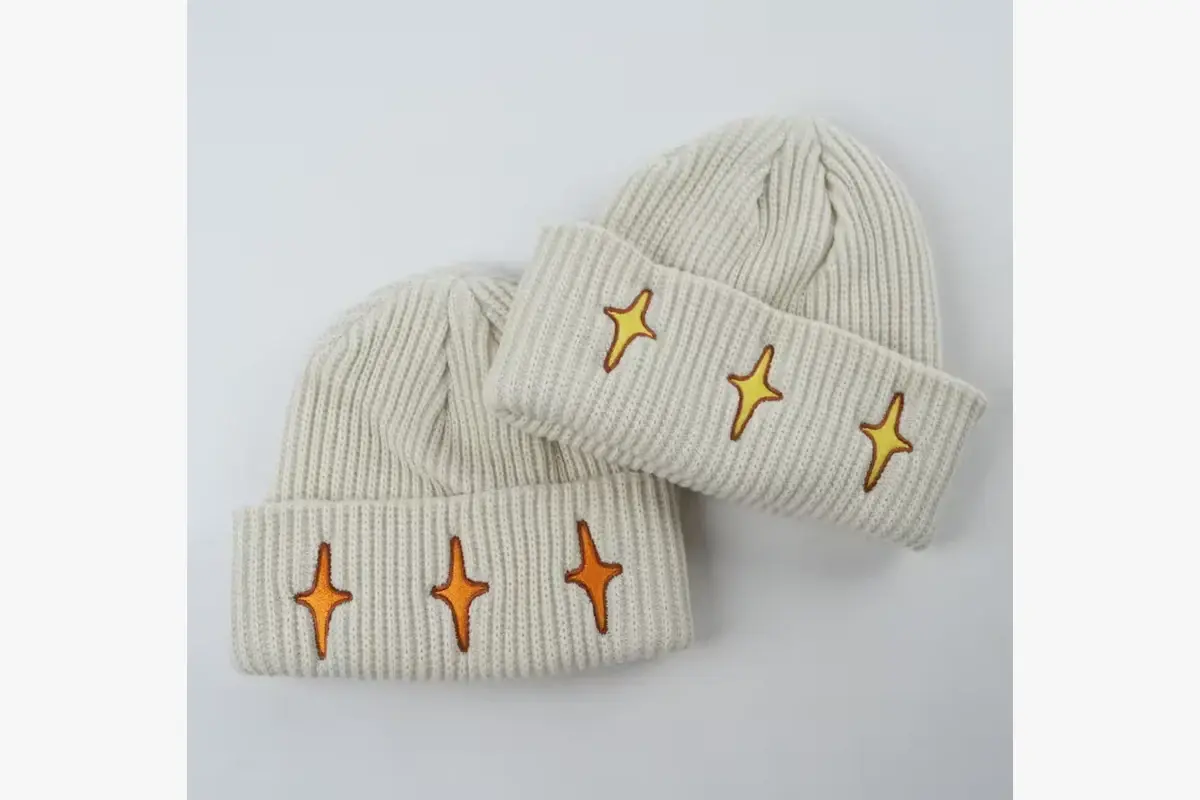 Two cream cuffed beanies with small star motifs embroidered on the knit