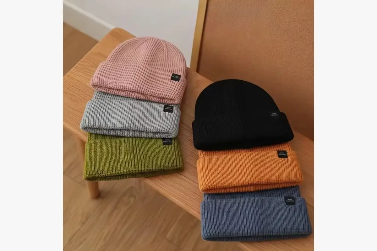 Cuffed beanies in several colors with small woven labels at the cuff edge