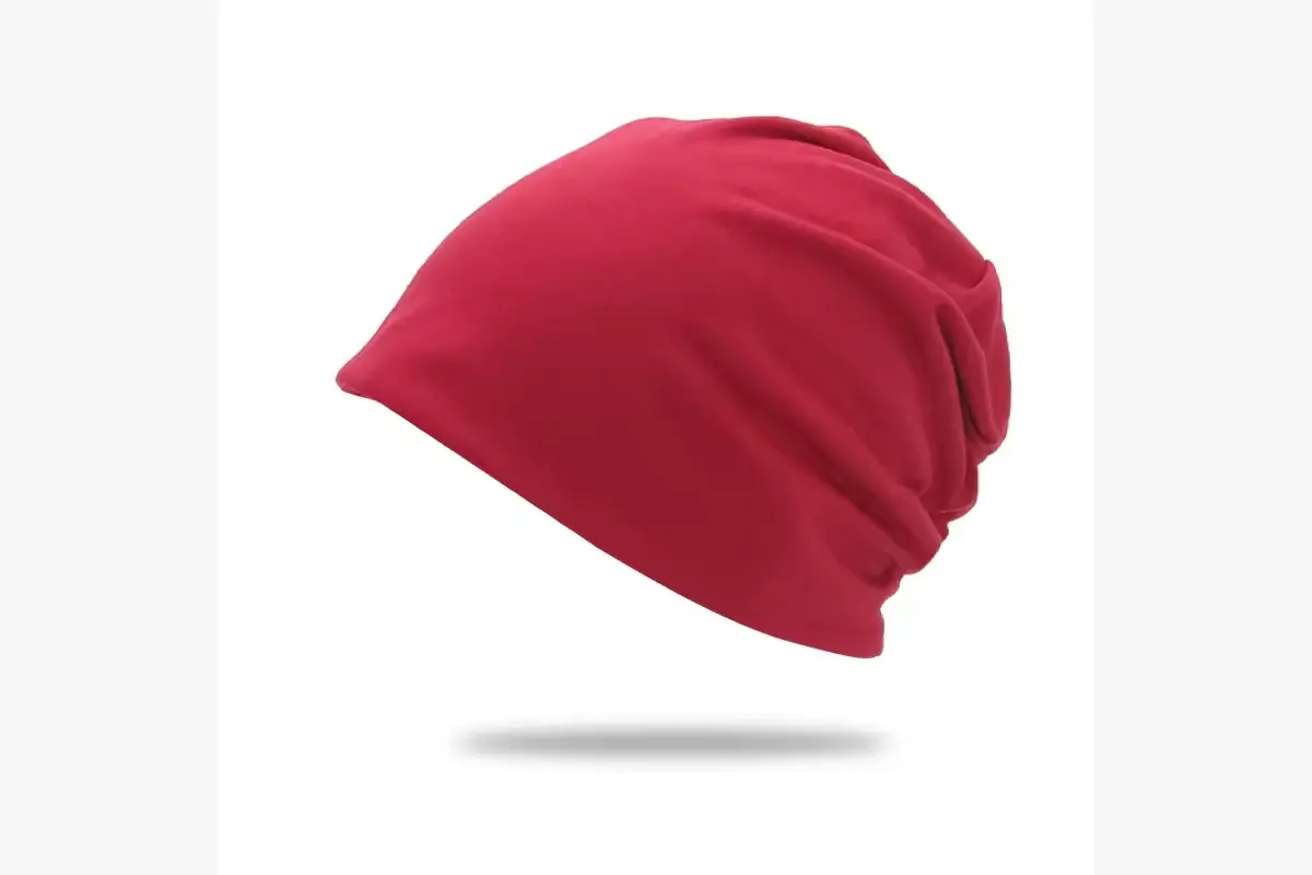 Red slouchy knit beanie shown from the side with fabric draping at the back