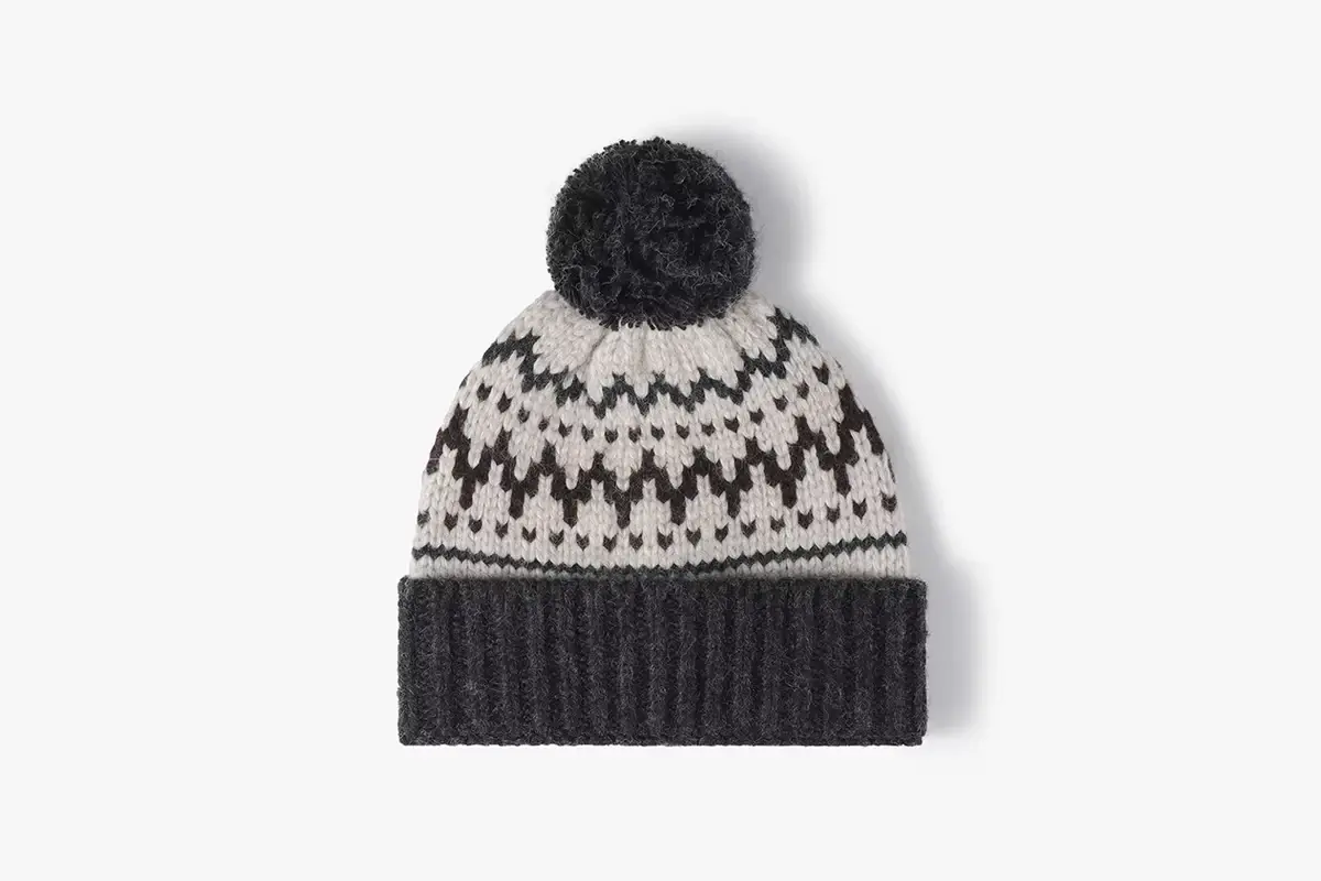 Black and cream pom pom beanie with a repeated knitted motif around the crown