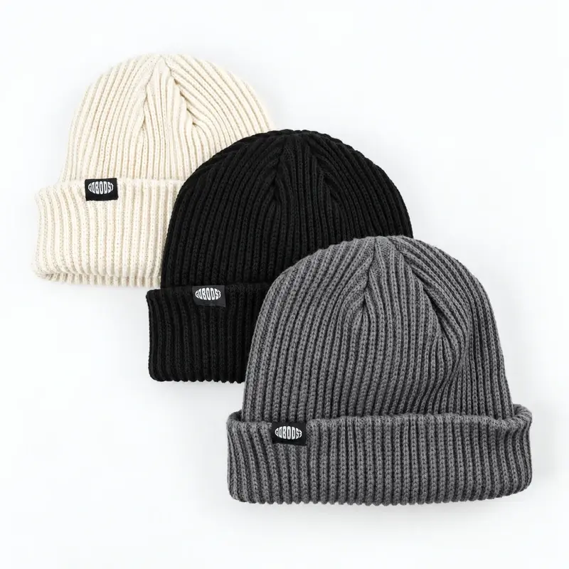 Three ribbed cuffed beanies in cream, black and gray with woven patches