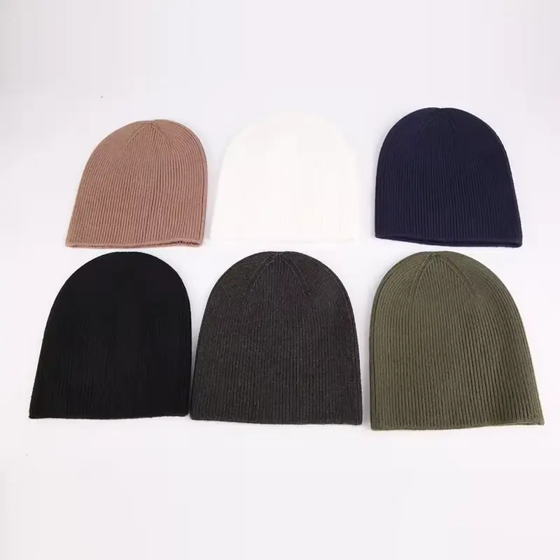 Six plain cuffless beanies in neutral colors