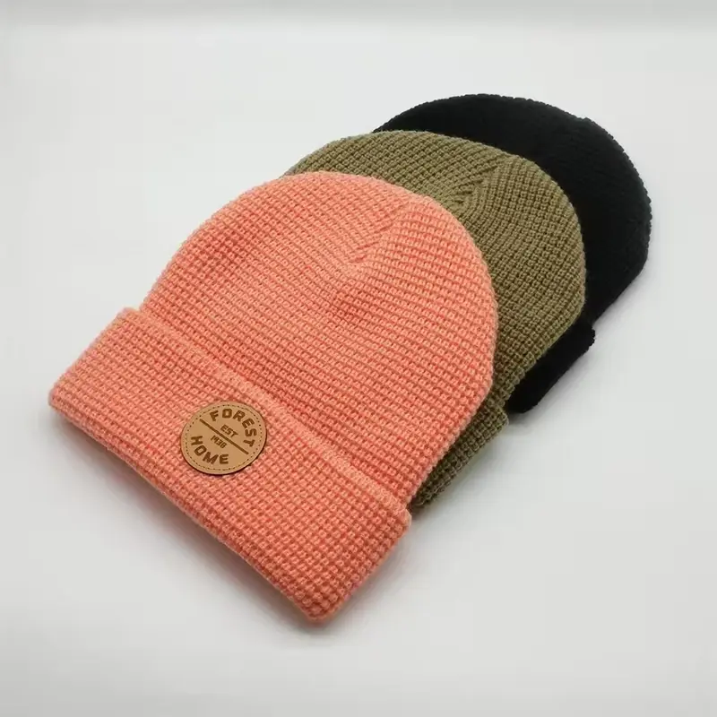Coral, olive and black waffle-knit fisherman beanies showing raised grid texture