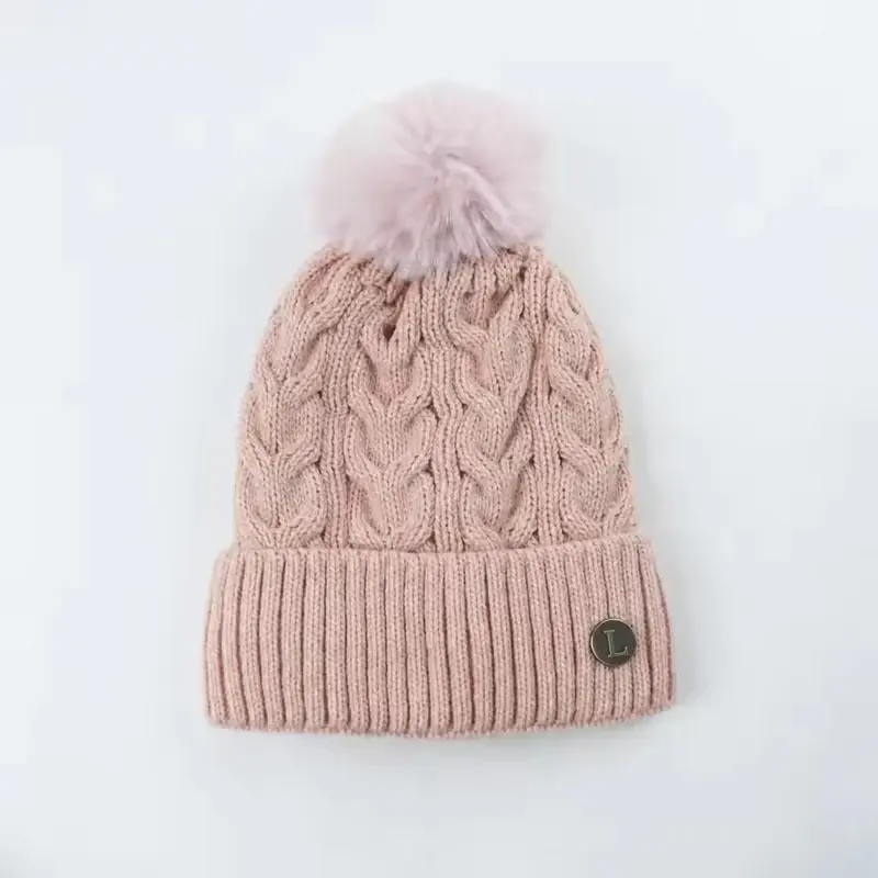 Pale pink cable-knit beanie with a fluffy pom-pom and folded cuff