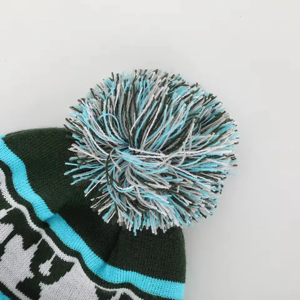 Close-up of a blue, white and black yarn pom-pom on a patterned knit beanie