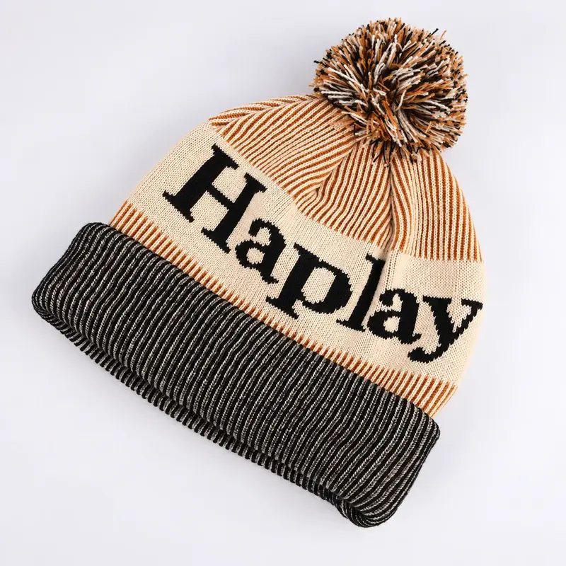Cream and black jacquard beanie with a tan yarn pom and folded cuff