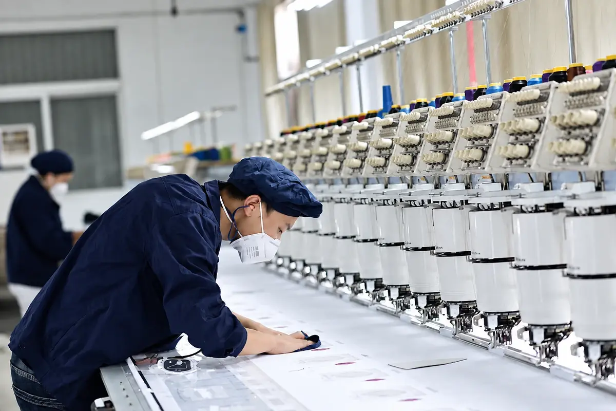 Worker operating knitting machines on the factory floor