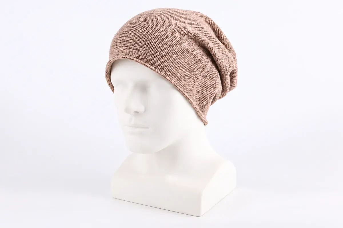 Light beige slouchy knit beanie in side profile with relaxed rear crown drape
