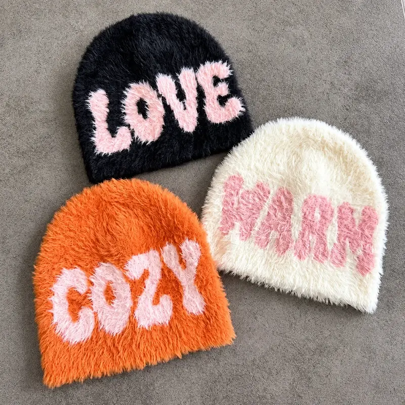 Three oversized knit beanies in black, orange and white with pink lettering