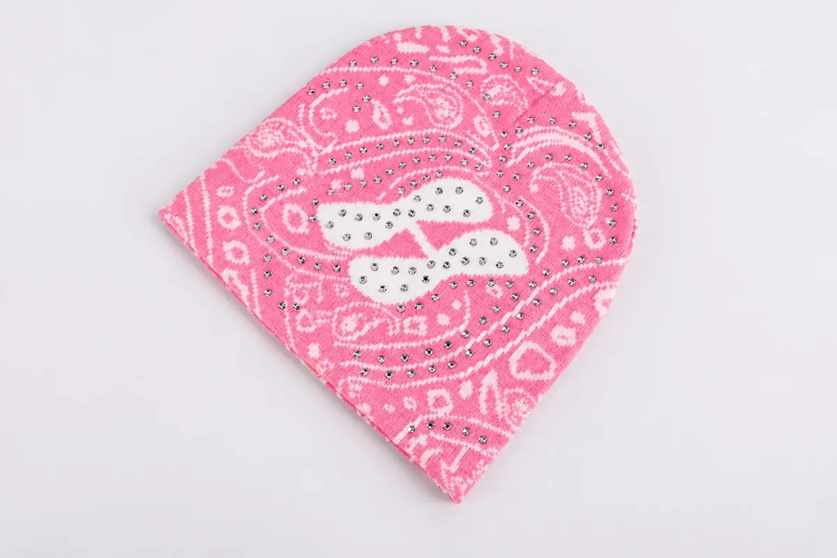 Pink patterned knit beanie with white design and decorative details