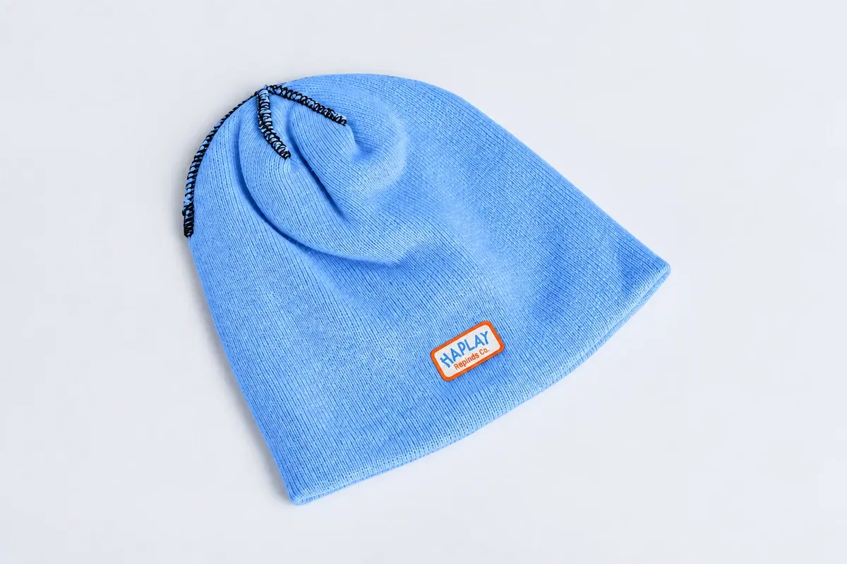 Pale blue fine-knit beanie with orange-bordered woven label