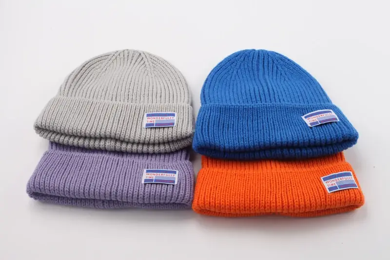 Four folded cuffed beanies with sewn front woven labels