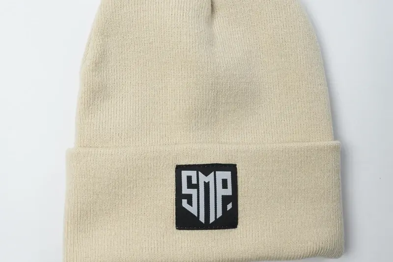 Cream ribbed cuff with a square dark logo patch