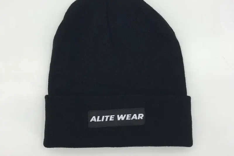 Black ribbed beanie with a small rectangular woven label on the cuff