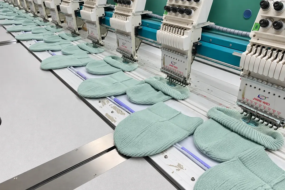 Mint knitted beanies under embroidery machines in the factory