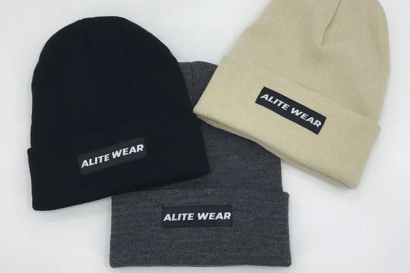 Three cuffed beanies showing woven labels on different colors and orientations
