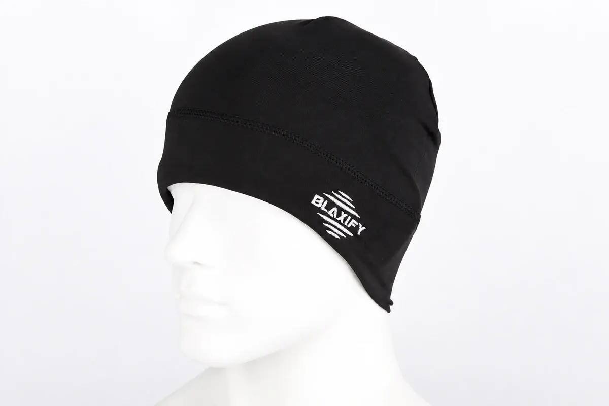 Profile of black cuffless knit beanie worn on a white mannequin, showing the unturned lower edge and embroidered mark