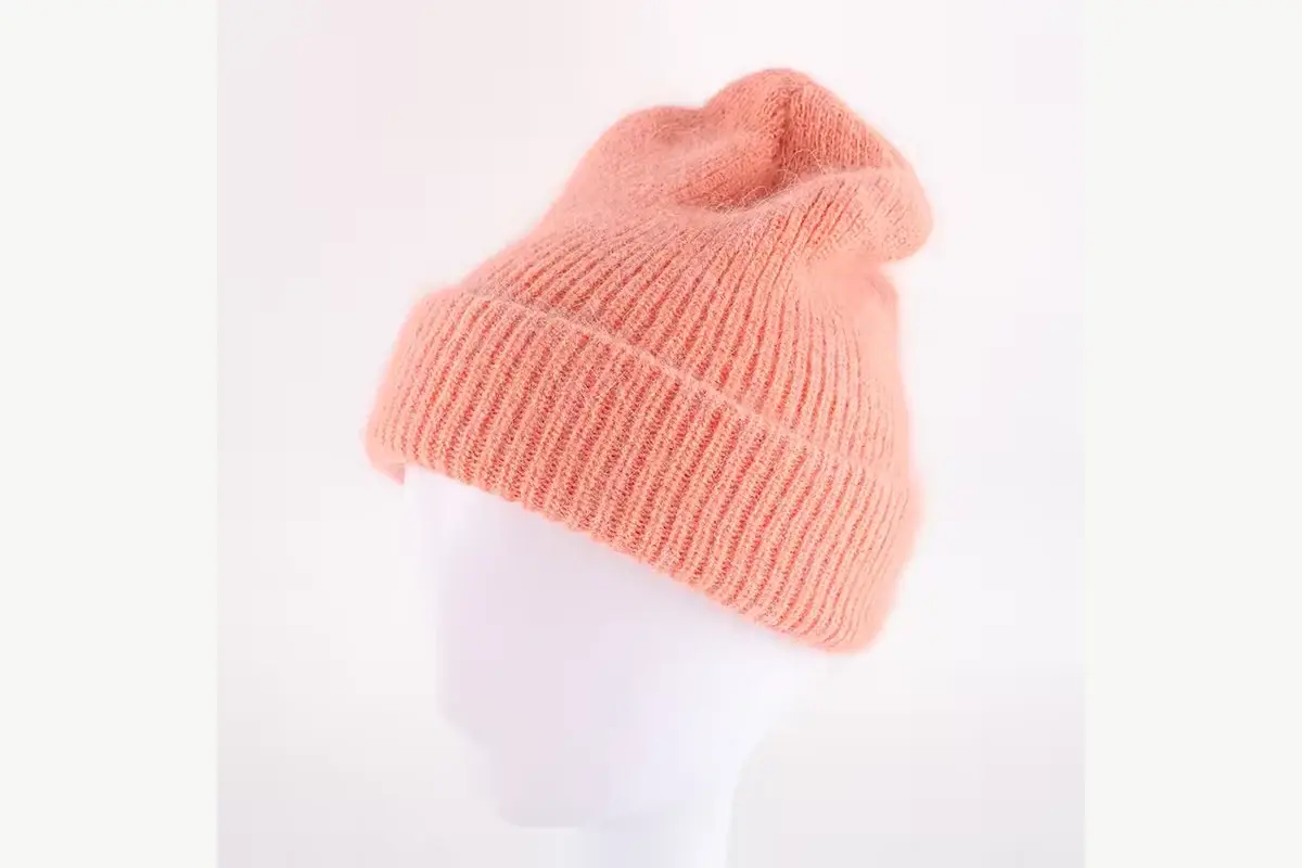 Soft pink rib-knit beanie shown on a display head