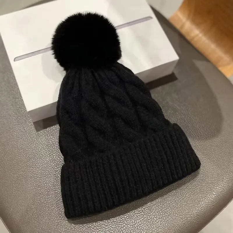 Black cable-knit beanie with a matching pom pom
