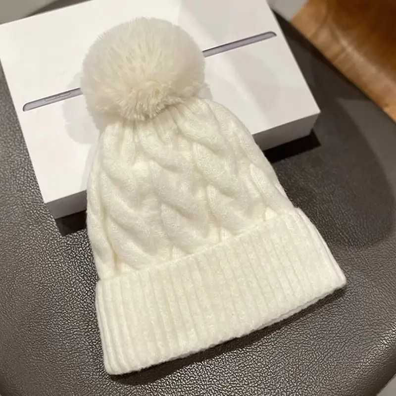 Cream cable-knit beanie with a matching pom pom