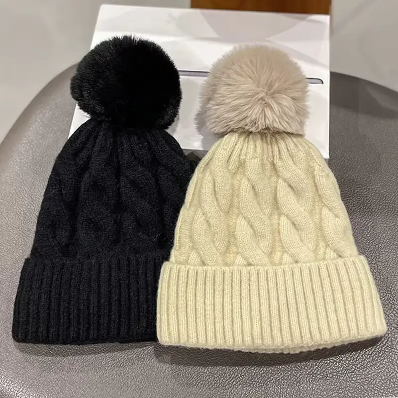 Black and ivory cable-knit cuffed beanies with pom-poms