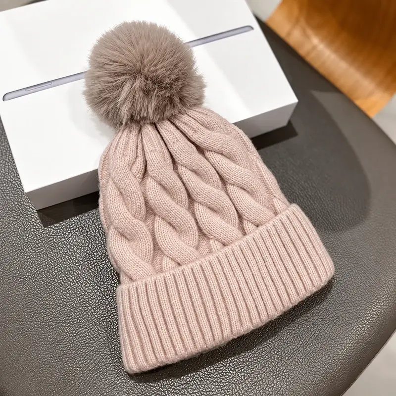 Pale pink cable-knit beanie with a gray-brown pom-pom