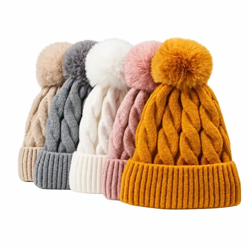 Five cable-knit pom-pom beanies in cream, gray, white, pink, and gold