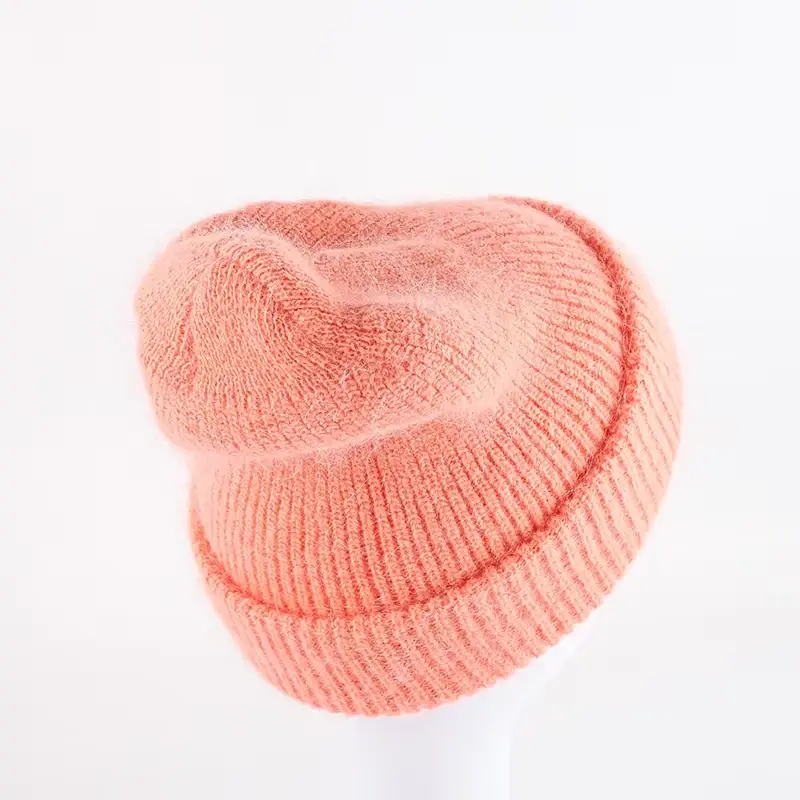 Peach pink slouchy knit beanie showing the crown and folded cuff