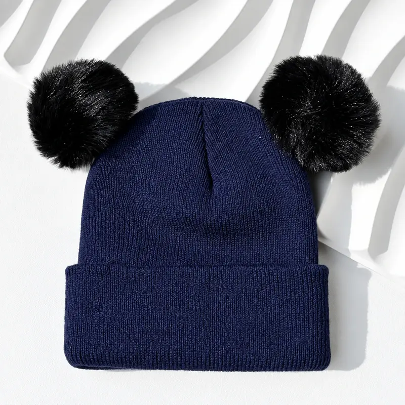 Navy rib-knit beanie with two black pom-poms and a folded cuff