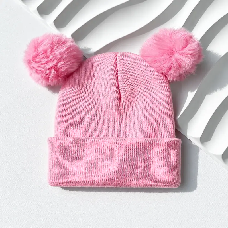 Pink rib-knit beanie with two pink pom-poms and a folded cuff
