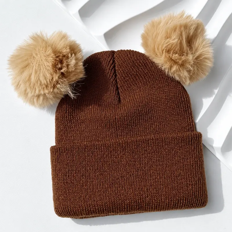 Brown rib-knit beanie with two oversized tan faux-fur pom-poms