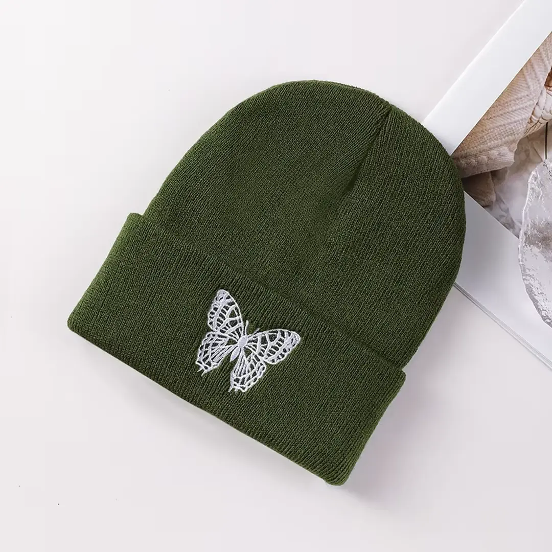 Olive knit beanie with a butterfly embroidered on the folded cuff