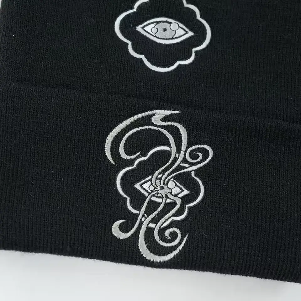 Close-up of white stitched motifs across a black knit beanie and cuff