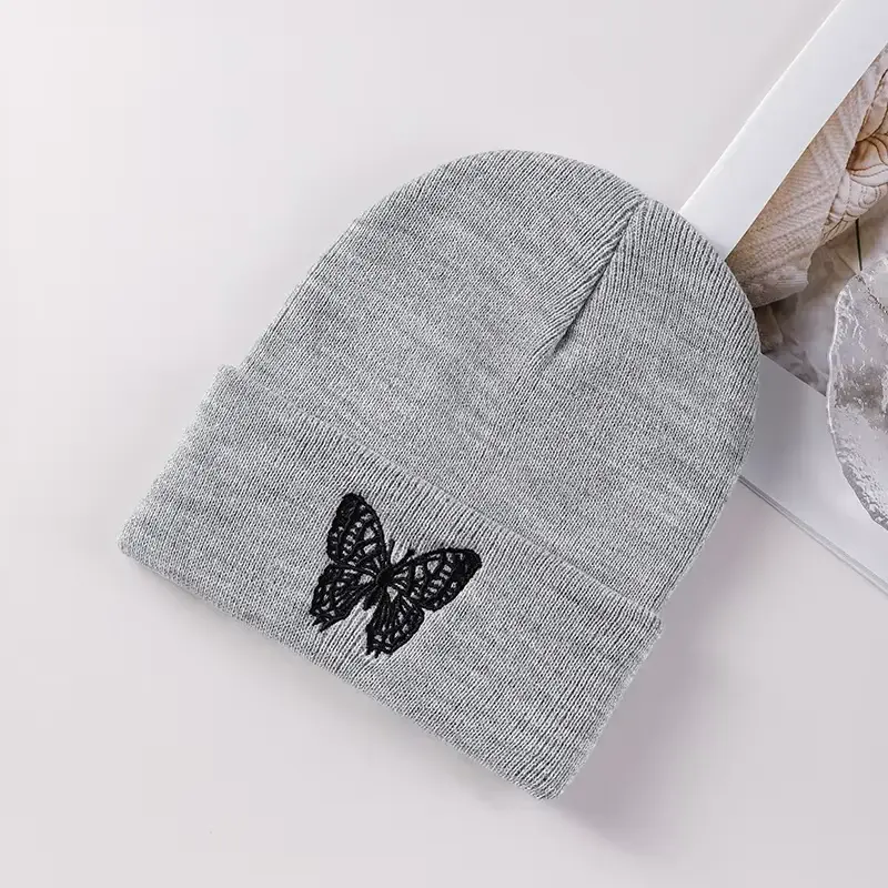 Gray knit beanie with a black butterfly embroidered near the brim