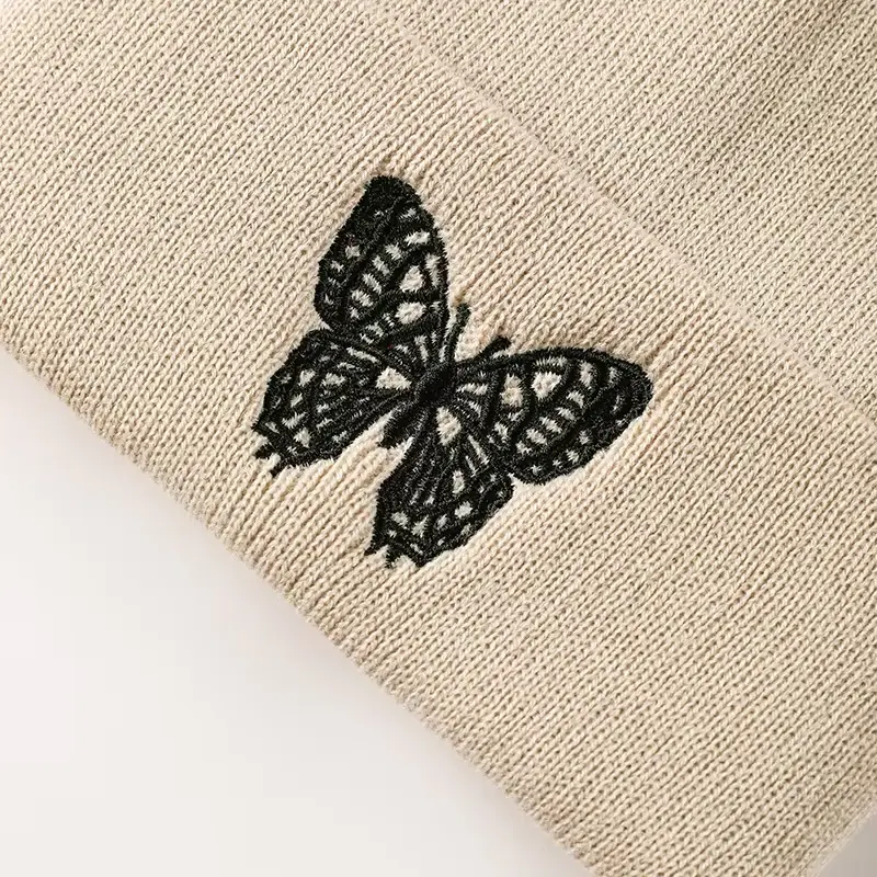 Black butterfly embroidery on cream knit fabric